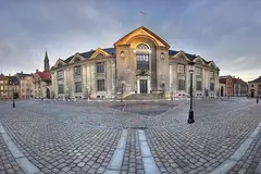 Главната сграда на Копенхагенския университет на павиран площад с фенери и исторически сгради наоколо
