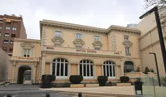 Жълтеникава класическа сграда с надпис British Council, арковидни прозорци, подстригани храсти и павиран площад отпред